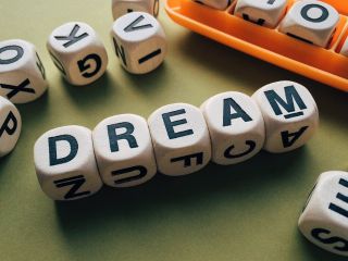 Alphabet character dices composing the English word "DREAM"