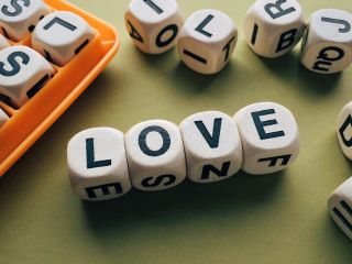 Alphabet character dices composing the English word "LOVE"