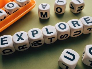 Alphabet character dices composing the English word "EXPLORE"